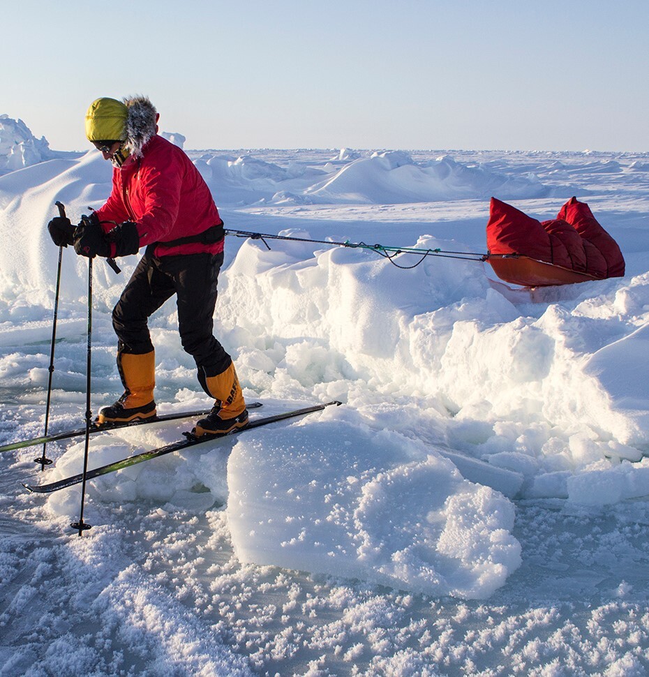 Skier dragging sled crossing an open lead on way to North Pole