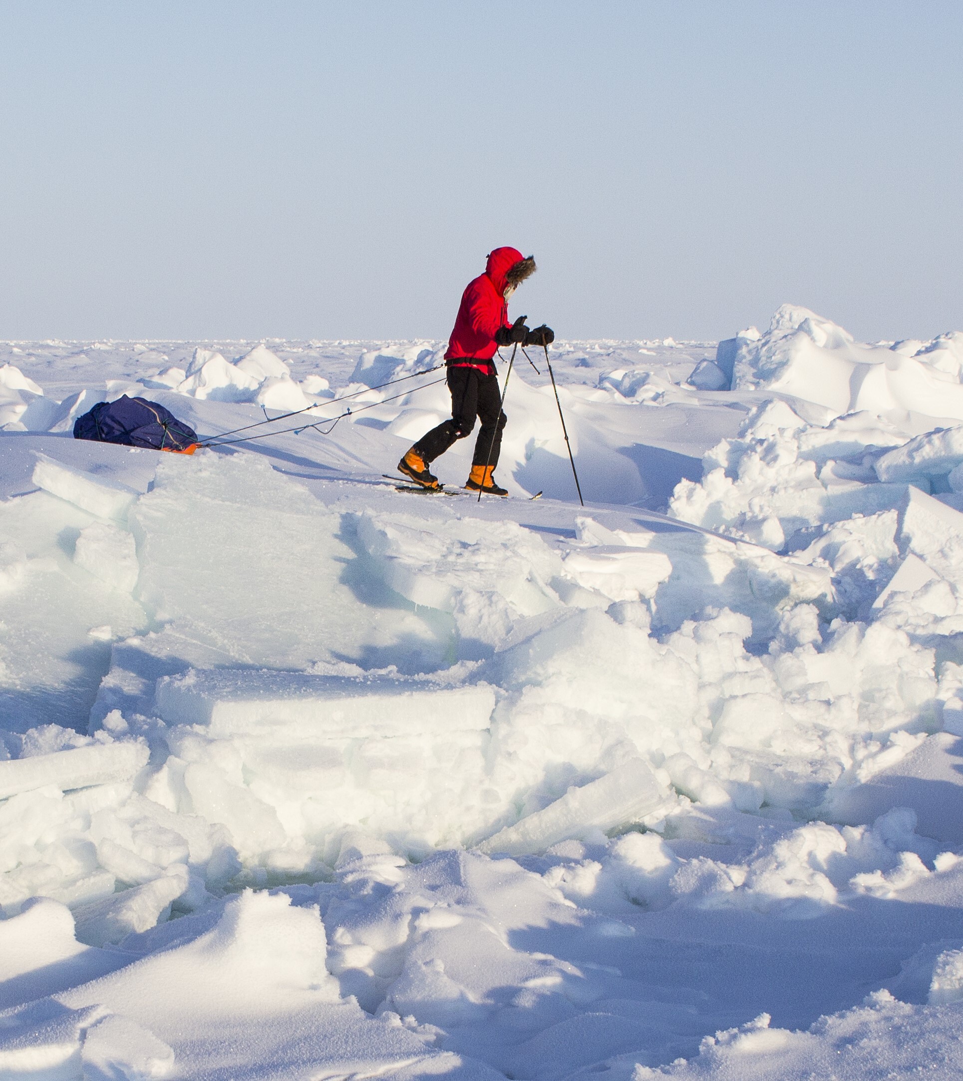Skier dragging sled crossing an open lead on way to North Pole