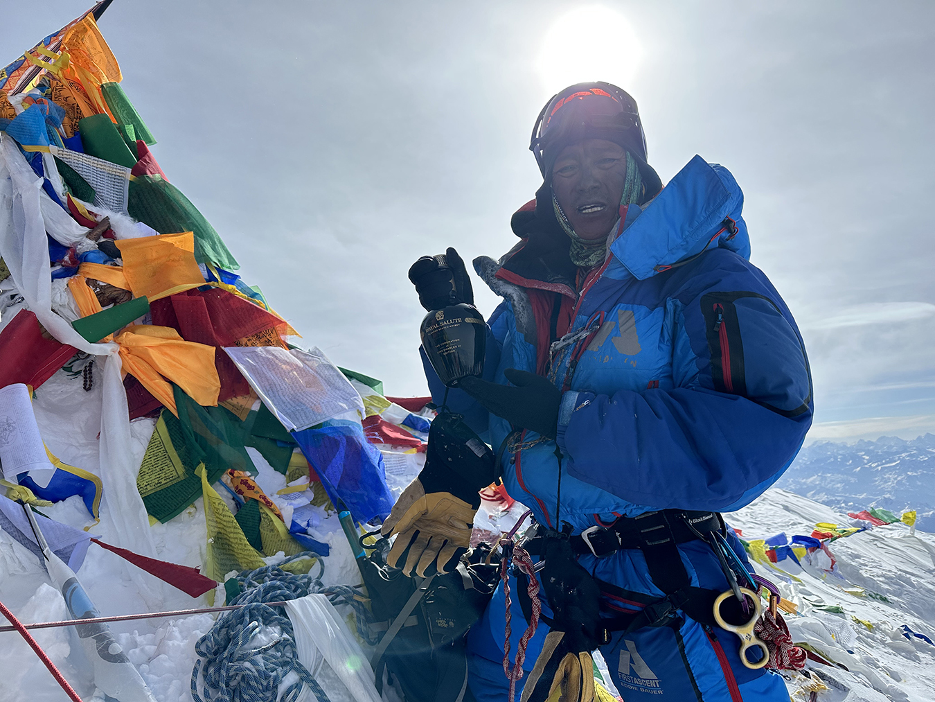 AC Guide Ang Dorjee Sherpa on the summit with the bottle of scotch he carried up there for charity in 2023.