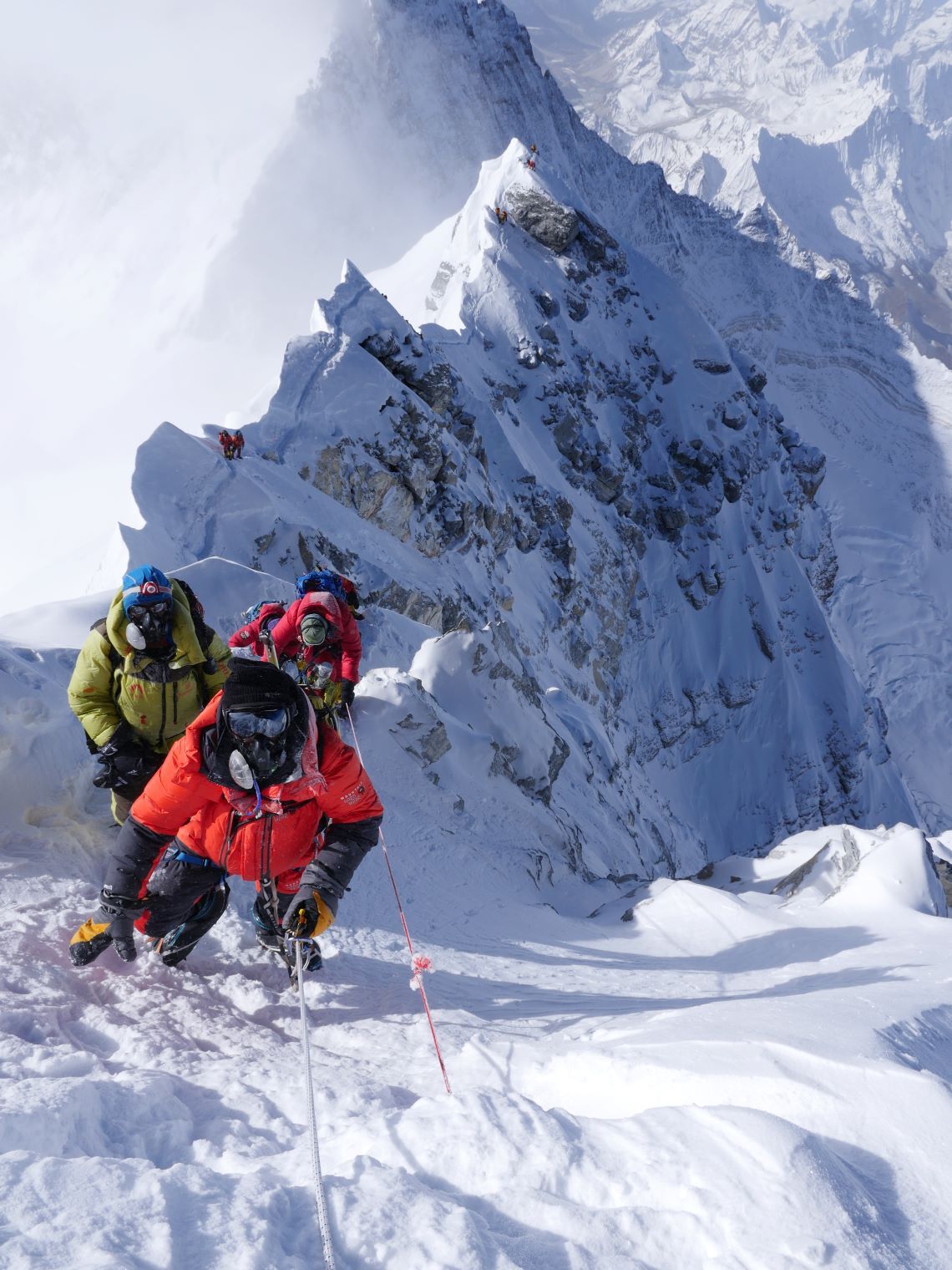 Climber on Hillary step Mt Everest with climbers behind on summit ridge