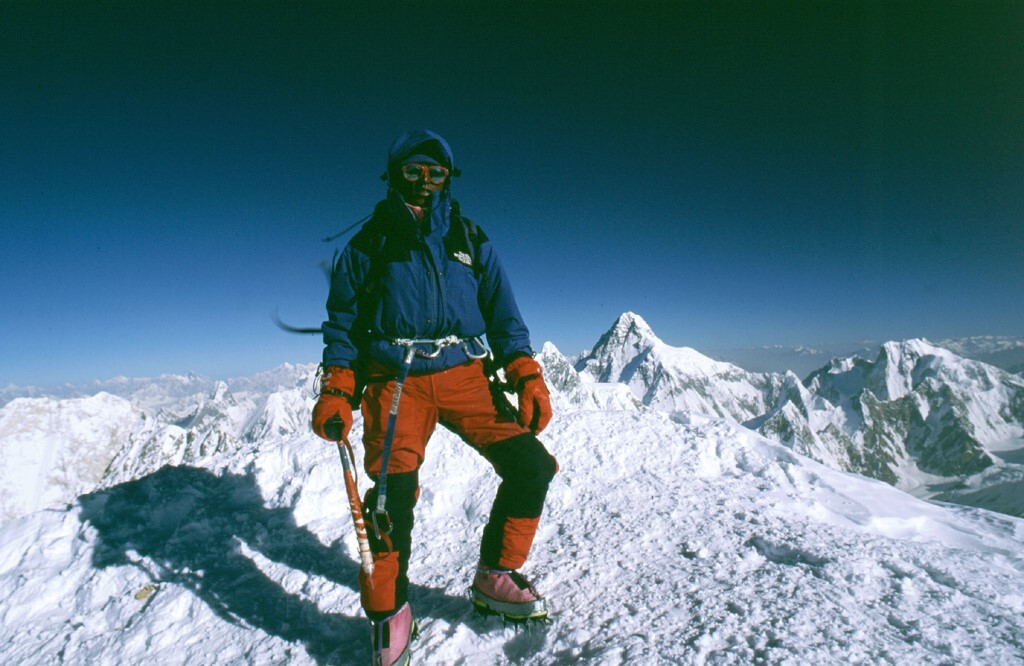 Climber on summit of Gasherbrum 2 with K2 behind