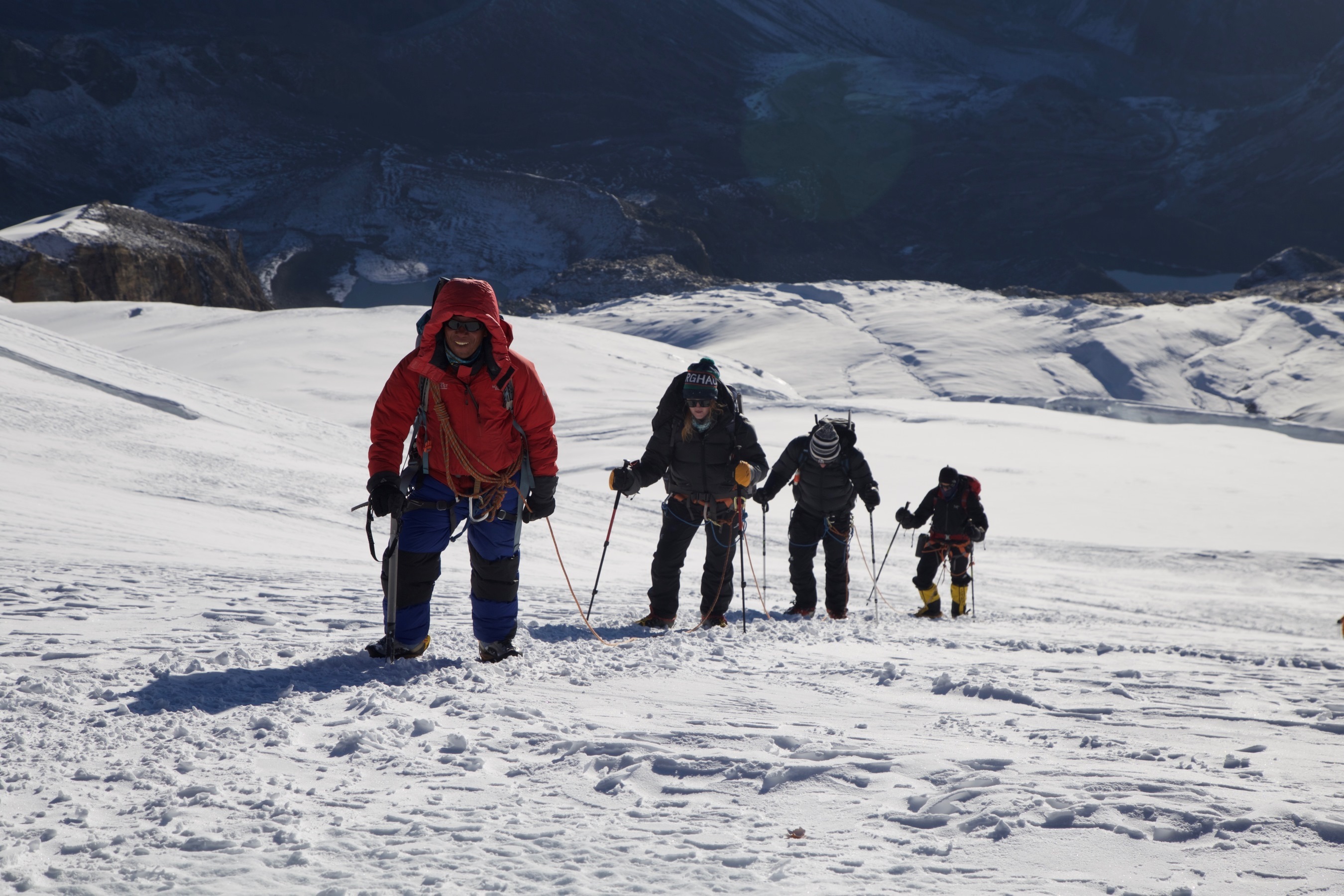 Traversing the glacier summit slopes, climbing roped together on Mera Peak