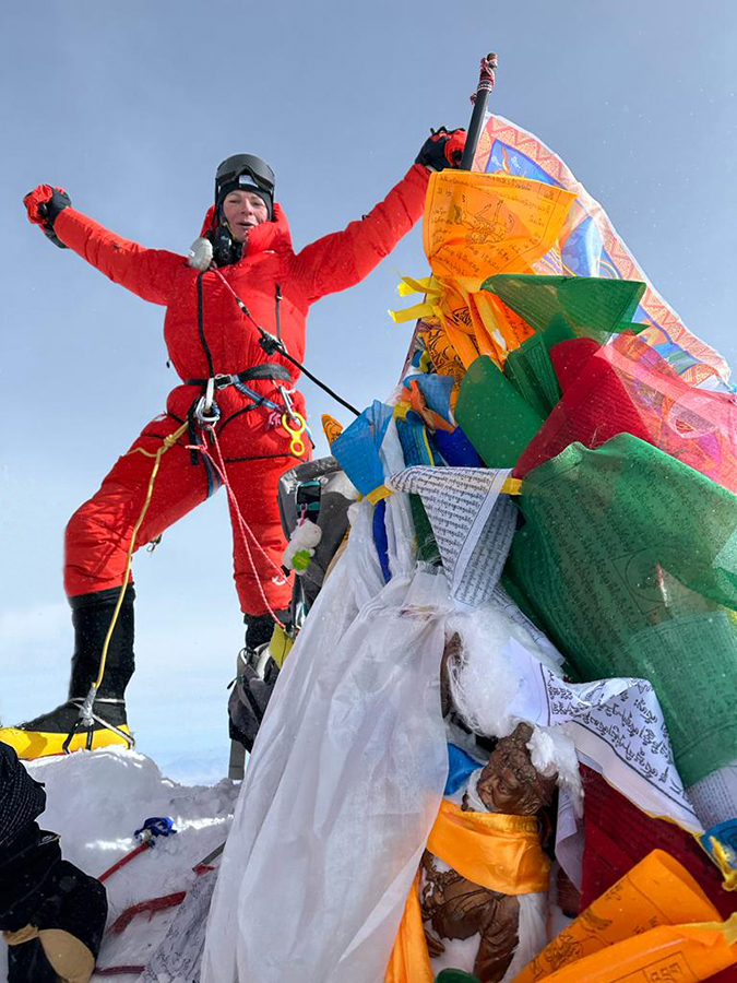 A climber stands proudly on the summit of Mount Everest
