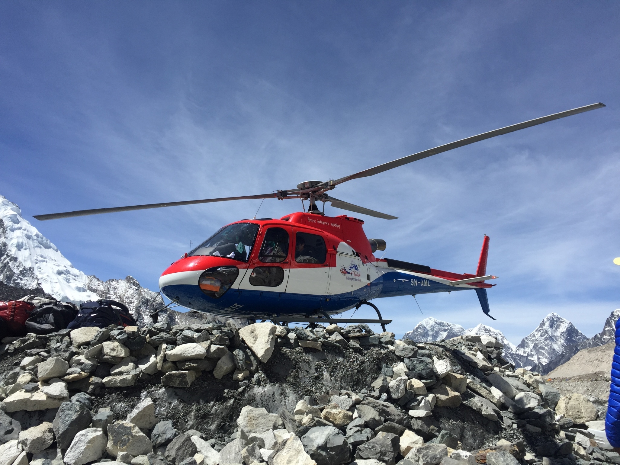 A red white and blue helicopter about to take off on a flight from Everest Base Camp