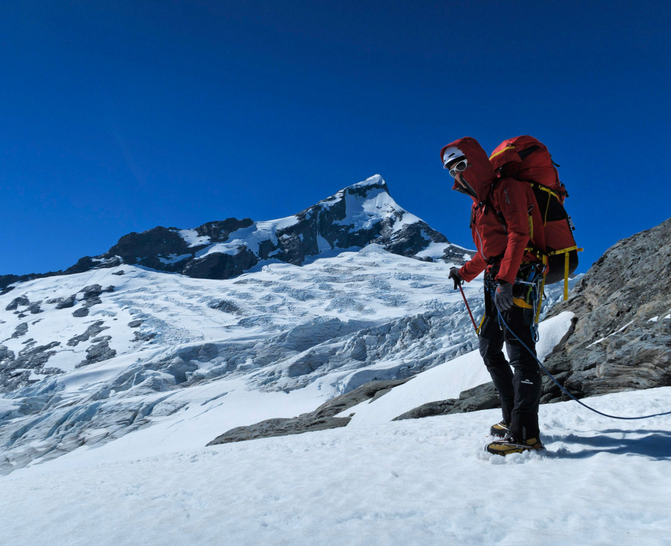 A climber participating in the Aspiring Guided Ascent with the majestic Tititea Mount Aspiring behind.